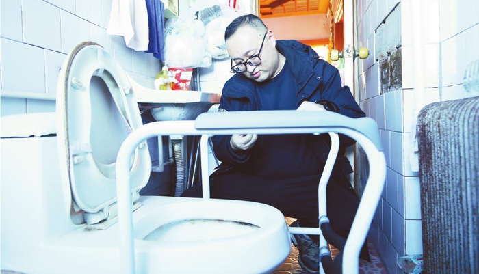         在盘锦市双台子区辽河街道，工作人员霍铁鑫为姜守义老两口调试马桶扶手。 张羽雁 摄