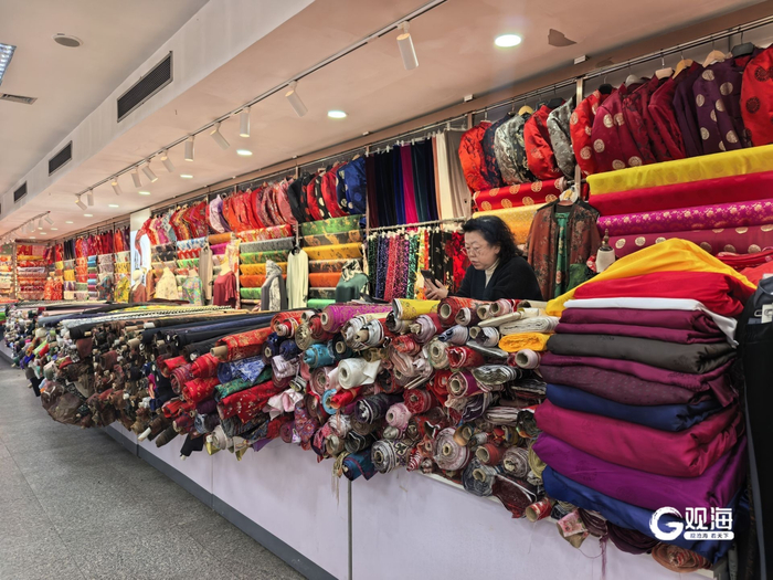 一家布料商店的柜台上陈列着各种花色、图案的布料。