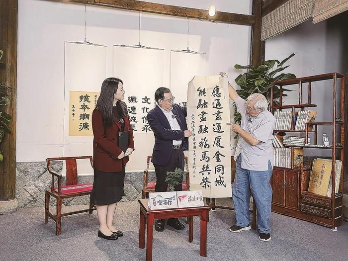    曹原彰（右）挥毫泼墨，用书法表达“同城生活圈”给金马乡亲带来的利好。本报记者 刘深魁 摄