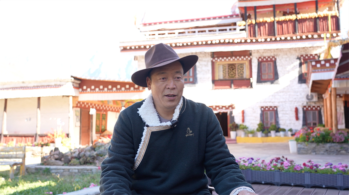 图为基卡依村的民宿老板降初介绍相关情况 摄影：陈浩力 