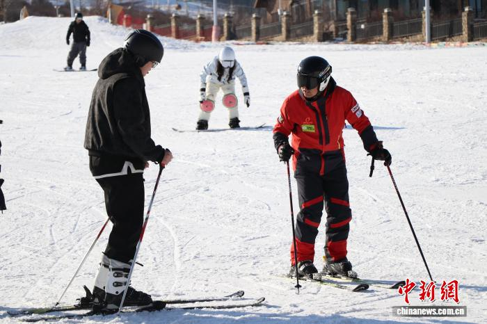 11月21日，巴孜尔别克·阿得里(右一)正在为游客讲解滑雪技巧。　苟继鹏 摄