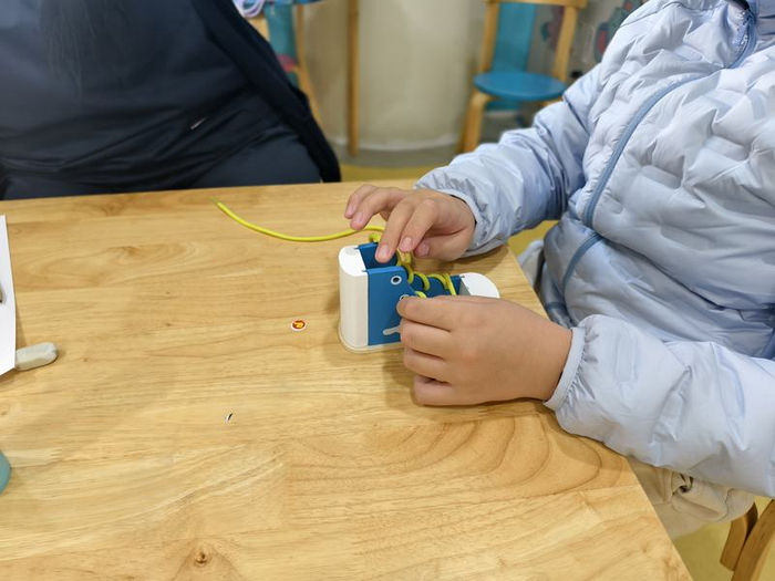 11月14日，大兴区妇幼保健院儿童康复园，一名康复儿童在自理课上练习系鞋带。新京报记者 刘思维 摄