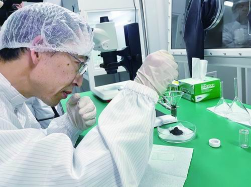 ▲祁生文对嫦娥六号月壤样品开展固定漏斗实验。