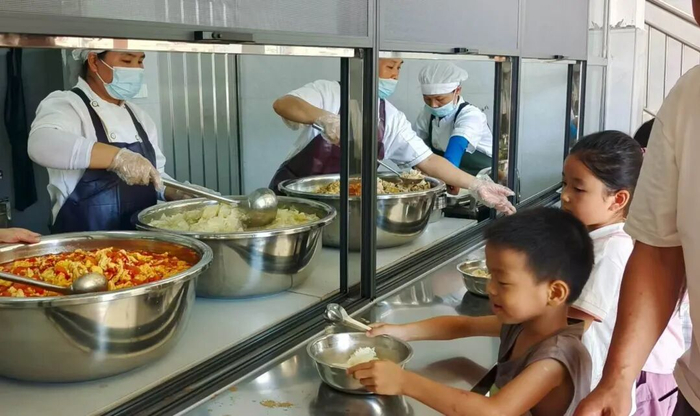 图为平桂区黄田镇英石小学学生在排队打营养餐