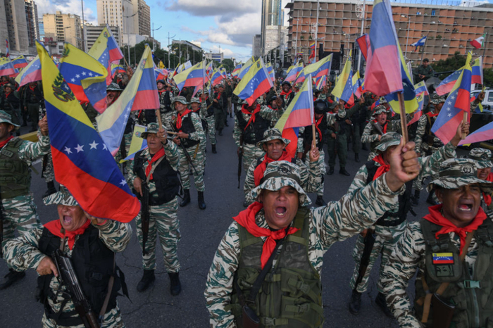 在委内瑞拉首都加拉加斯，民兵组织成员挥舞委内瑞拉国旗参加游行。新华社发（马科斯·萨尔加多摄）