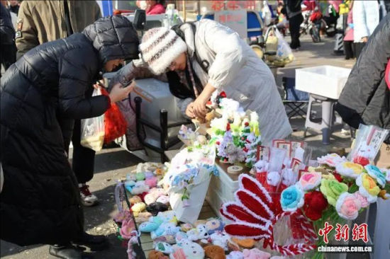 12月8日，年轻人在临沂曹洼大集上选购手工编织品。李明芮 摄