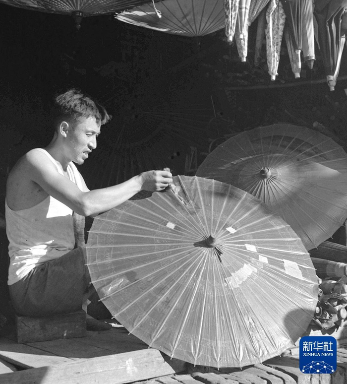 1960年，江苏南京古楼人民公社山西路修伞组工人为顾客修伞。新华社记者 朱冰菊 摄