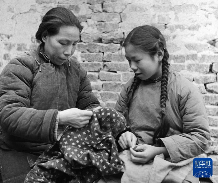 1958年，湖北孝感朋兴乡和平二社的一名妇女（左）教女儿缝衣服。新华社记者 郝纯一 摄