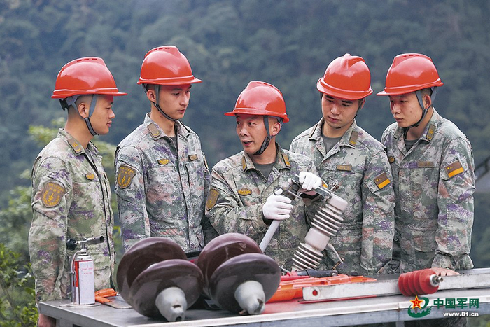 　　火箭军某旅一级军士长安军伟（中）为战友讲解某设备内部结构。向修红摄