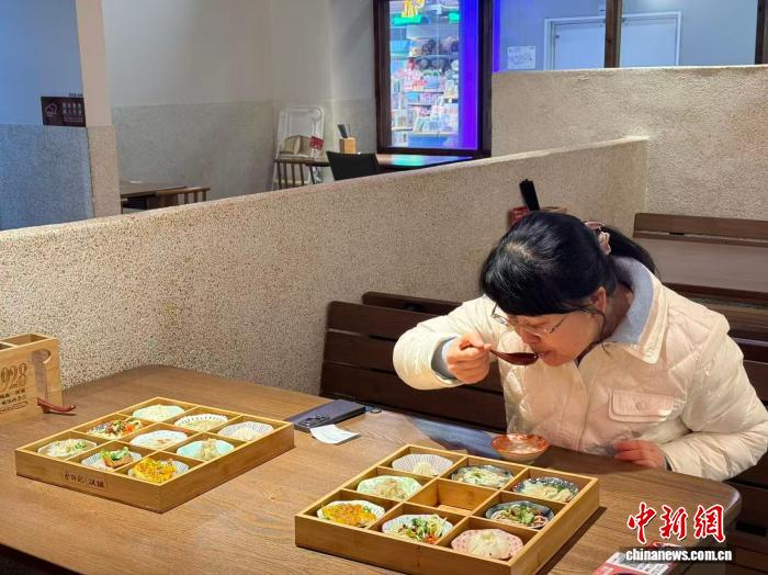 12月18日，一位食客正在品尝“九宫格过早”拼盘。武一力 摄