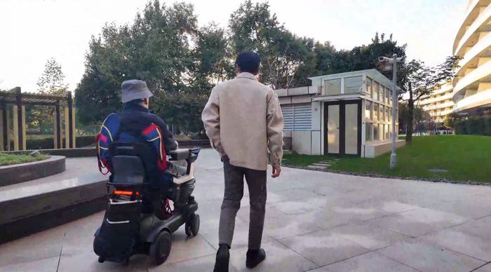 高位截瘫患者（左）通过脑智卓越中心等单位研发的脑机接口系统意念控制轮椅