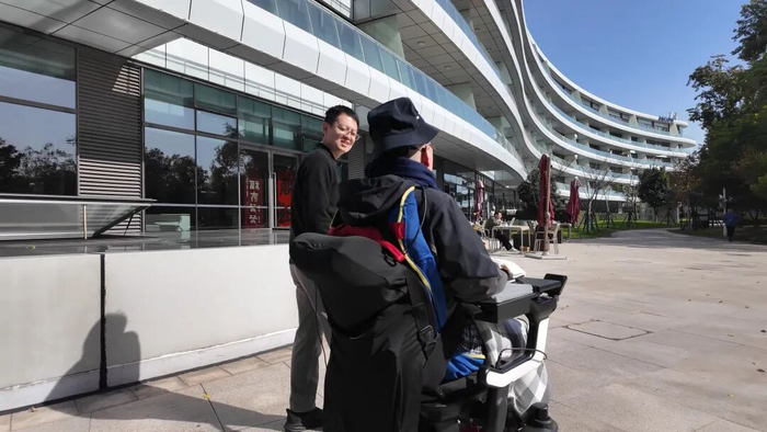 第二例临床试验参与者在脑控轮椅过程中与赵郑拓（左）交流控制体验