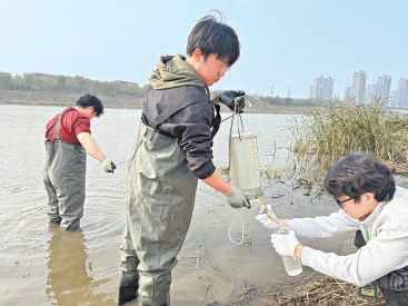 学生们相互配合收集水样。本报记者 陈强 摄