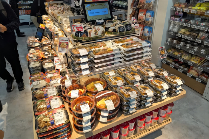 入口貨架上密密麻麻地擺放著現(xiàn)制便當、飯團、油炸食品