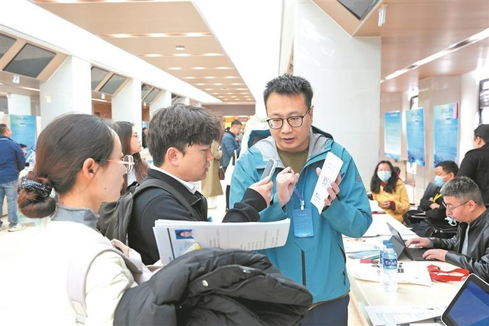 招聘会现场，学生用手机扫描青海企事业单位提供的二维码，便捷获取岗位信息，现场沟通高效顺畅。