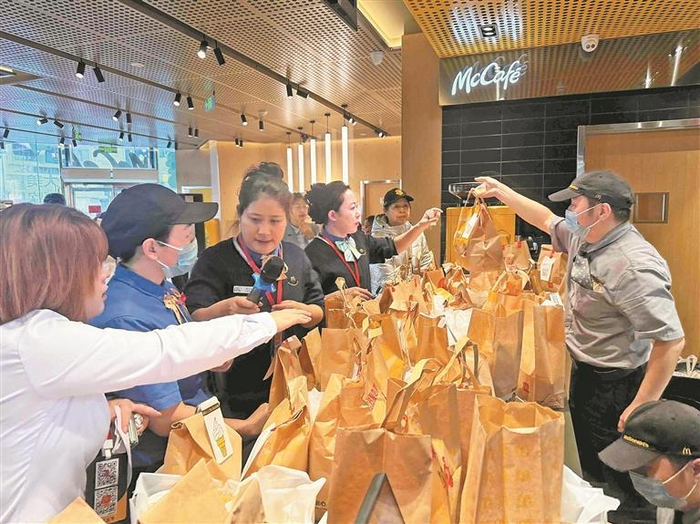 麦当劳店内工作人员正紧张有序地打包餐品，堆满桌面的纸袋彰显出开业首日的火爆消费需求。
