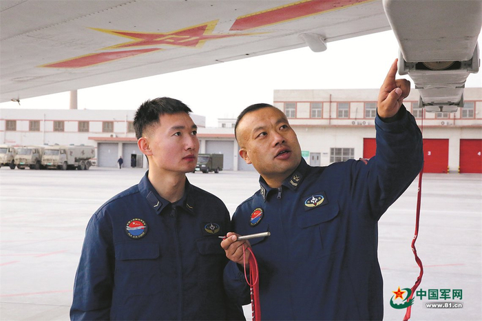 　　王永（右）为战友讲解装挂流程。陶远邦摄