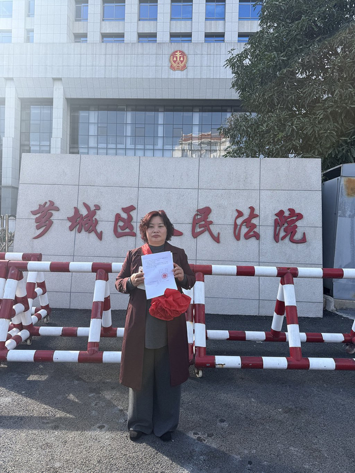 芗城区法院门口，林惠荣手持无罪判决书。图 王殿学