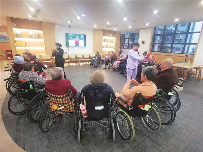     图为重庆解放碑宜康百龄帮养老服务中心里，工作人员正在与老人们互动。    程晖 摄