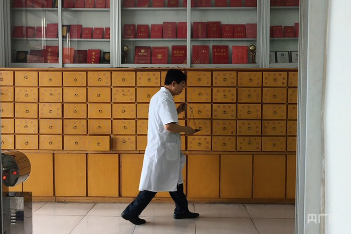 中药柜上，摆着数十份梁春荣的荣誉证书（央广网记者  白德彰  摄）
