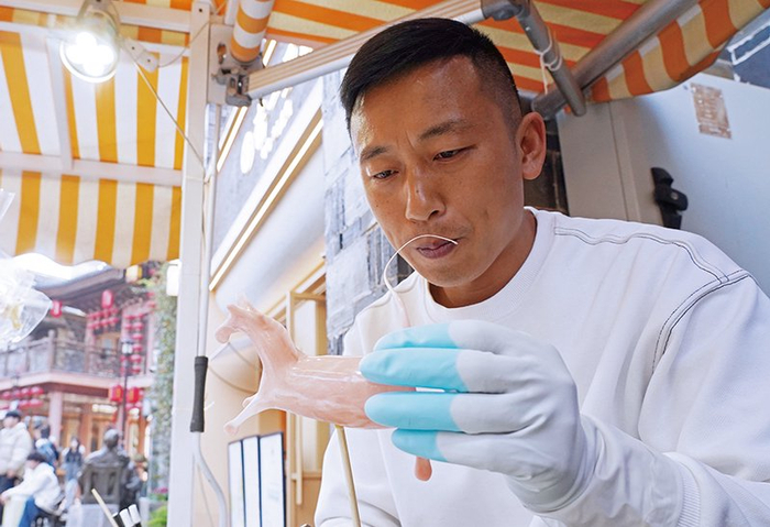 ▲“小马”形状的糖人在熊传发指尖上渐渐成形，像被注入了生命一般活灵活现。