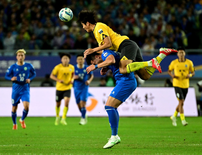 2025年10月18日，在“苏超”半决赛中，泰州队球员（上）与南京队球员争顶头球。新华社发（曹政 摄）