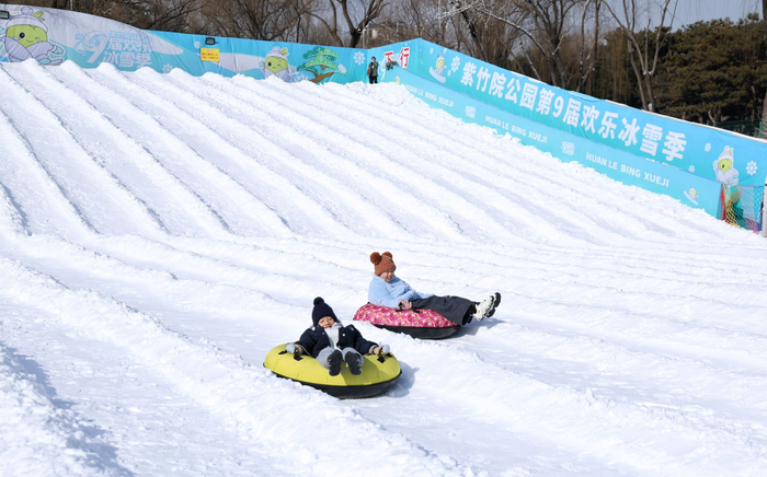 12月26日，紫竹院公园第九届欢乐冰雪季，游客在玩“雪上飞碟”。新京报记者 薛珺 摄