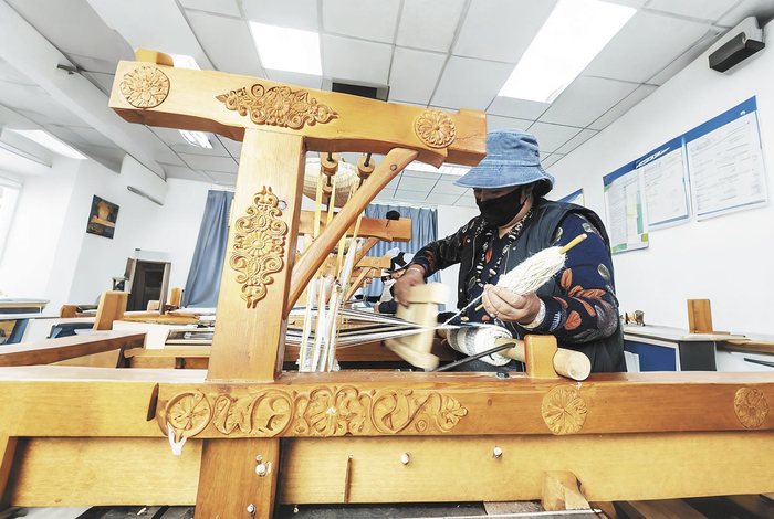 ↑花石峡镇东泽村文创产品研发基地中，放下牧鞭的牧民正在加工手工绒毛制品。东泽村文创产品研发基地供图