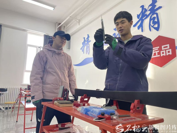 12月3日,朱万鹏(右)教学生进行雪板维护。石榴云/新疆日报记者 赵西娅摄