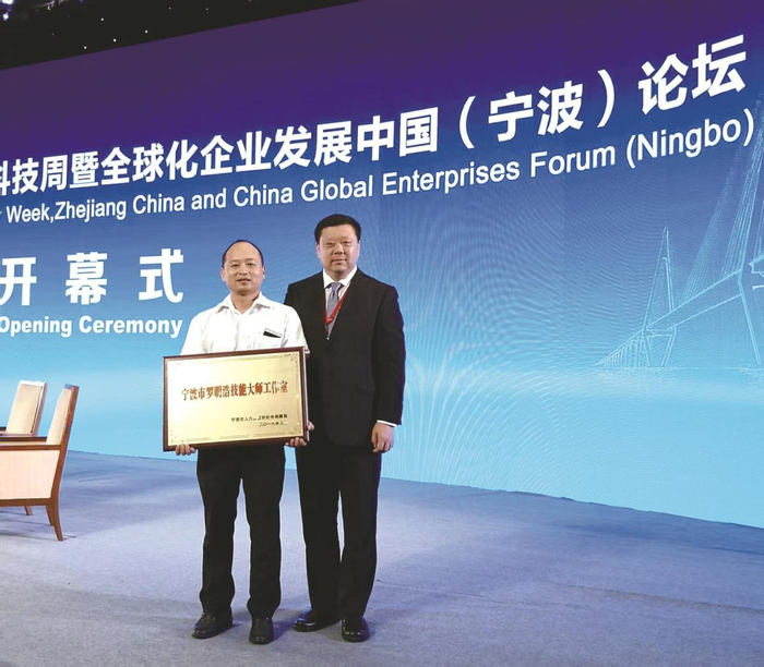 2016年，宁波市罗明浩技能大师工作室授牌现场，罗明浩（左）与姚力军的合影。