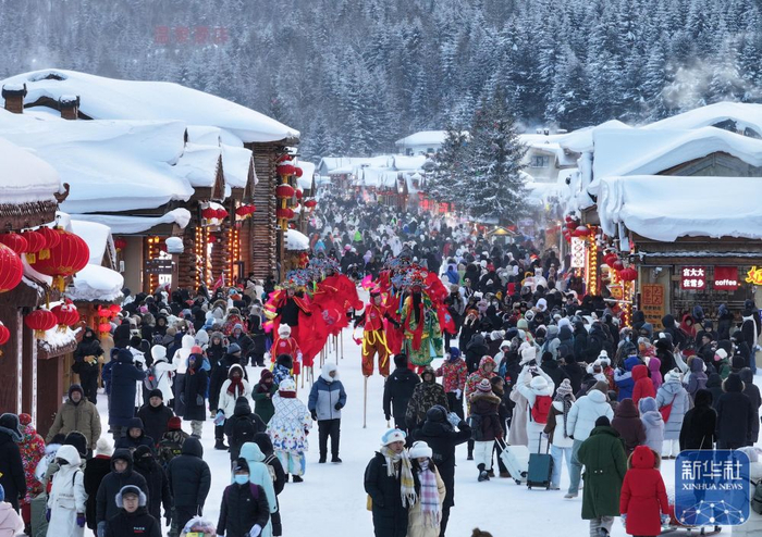 ↑ 1月1日，游客在位于黑龙江省牡丹江市的“中国雪乡”景区雪韵大街上欣赏踩高跷表演（无人机照片）。新华社发（孙庭义 摄）