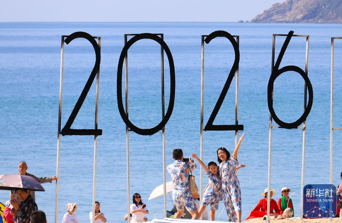 ↑ 1月1日，游客在海南省三亚市大东海旅游区拍照。新华社发（李学仕 摄）