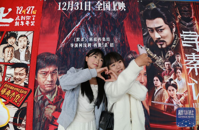 ↑ 1月1日，在云南省蒙自市一家电影院，观众与电影海报合影。新华社发（薛莹莹摄）