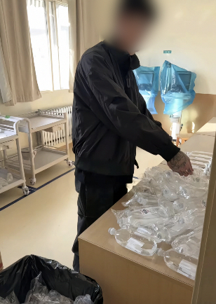 ▲视频中，文身男子穿着便服，在护士站内帮其护士女友配药、给点滴瓶贴标签。图/潇湘晨报