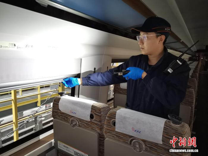 图为作业人员对动车组车内窗帘进行检查。 李各 摄