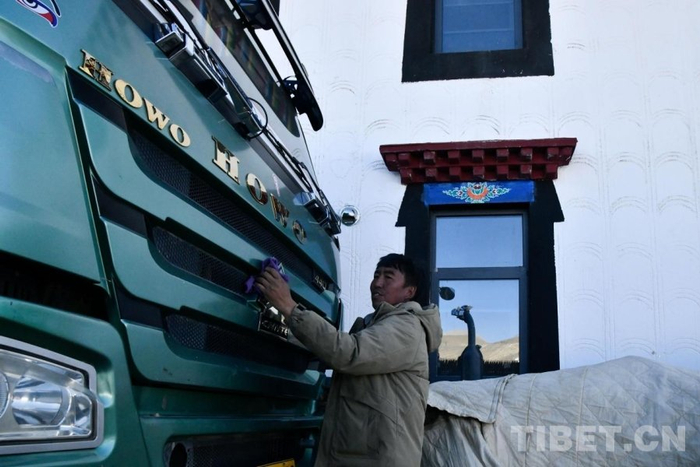 图为旦增杰布正在新家前擦拭自己的新车 摄影：赵振宇