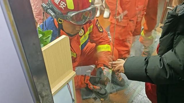 消防员用工具扩张玻璃门缝隙。图源：安徽消防 