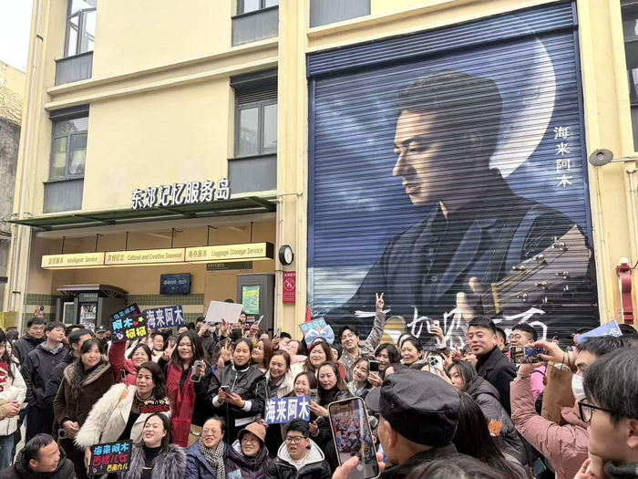 海来阿木在涂鸦墙前和粉丝合影
