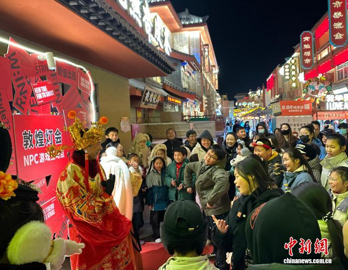 　　2026年1月9日晚，甘肅敦煌，游客與“財神”游戲互動。中新社記者?丁思?攝