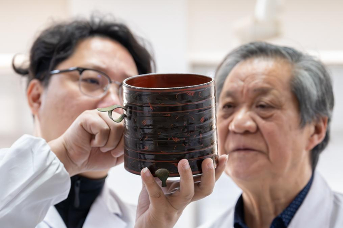 　　1月9日，在荆州文物保护中心，吴顺清（右）与吴昊在查看一只修复好的漆樽。新华社记者 杜子璇 摄