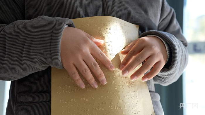 夏孝嚴手指輕撫盲文（央廣網記者 劉暢司晨 攝）