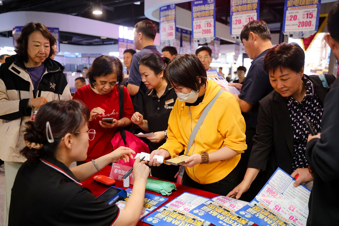 2025年市区爱特购物中心，市民咨询家电补贴政策。陈康摄