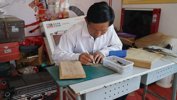 魏岳成雕刻皮影。