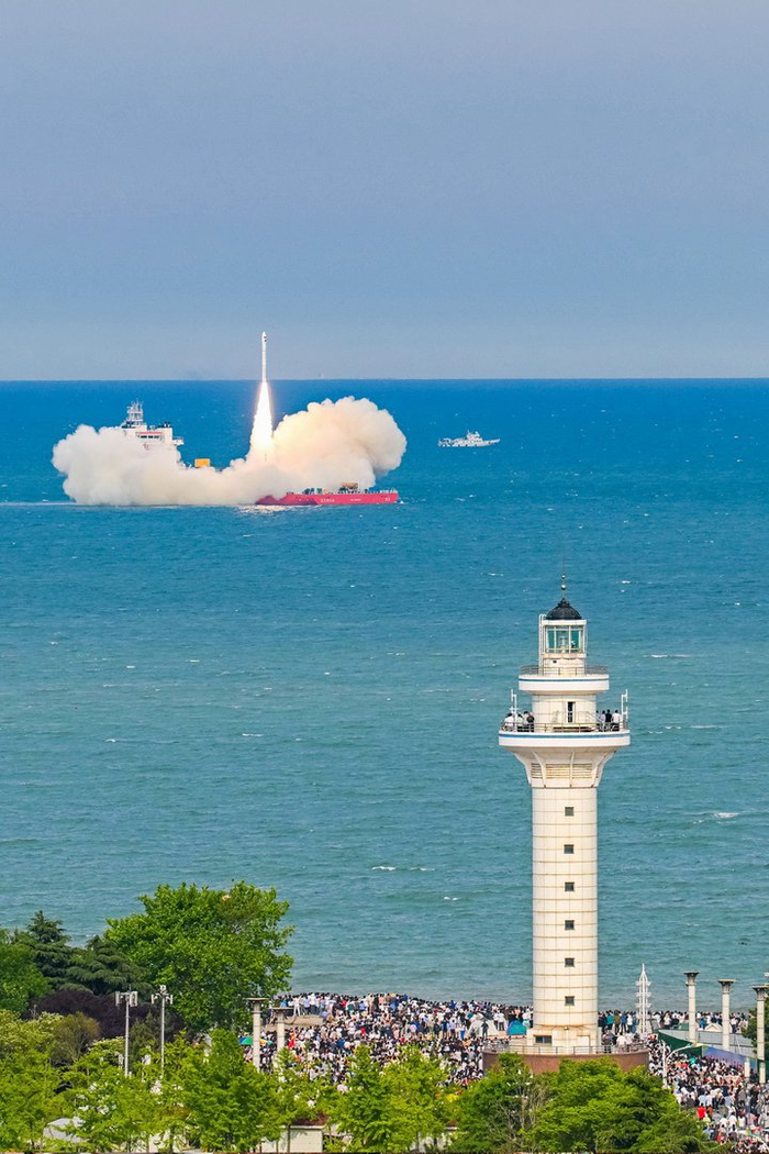日照万平口，观看火箭发射的人群站在岸边。摄影薄林