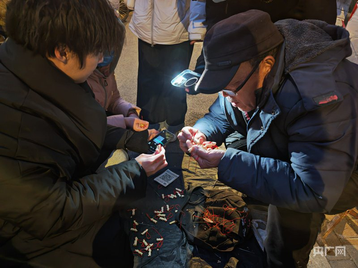 天色漸暗，有顧客用手機(jī)為大爺打光（央廣網(wǎng)記者 龐婷 攝）