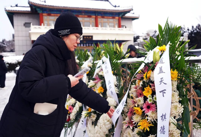 1月18日，一名吊唁者在整理花圈。新华社记者 潘旭 摄