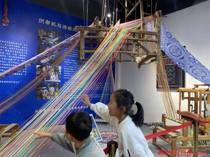 （图为孩童正“深山集市”感受织布机的魅力。怀化日报全媒体记者 罗单 摄）