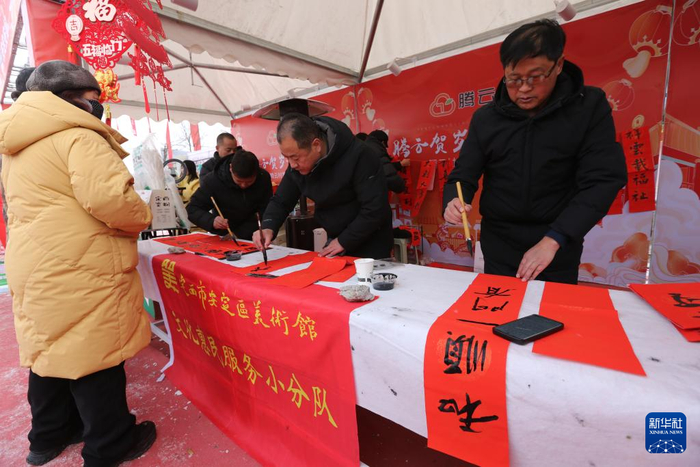 定西市安定区美术馆组织的书法爱好者在年货大集上为群众写春联（1月19日摄）。新华社发（王克贤 摄）