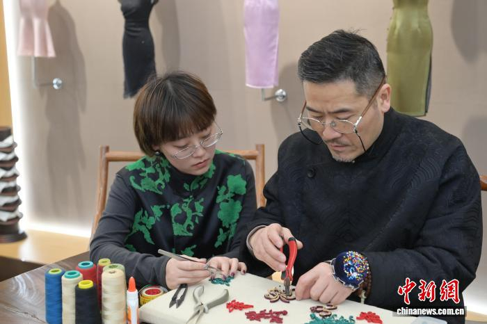1月20日，安徽合肥的“徽帮裁缝”店内，王俊在教女儿王书仪制作盘扣。付敏 摄
