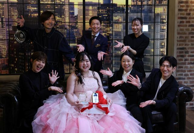 野口（中）捧着手机里的“新郎”与婚礼工作人员合影。图：GJ